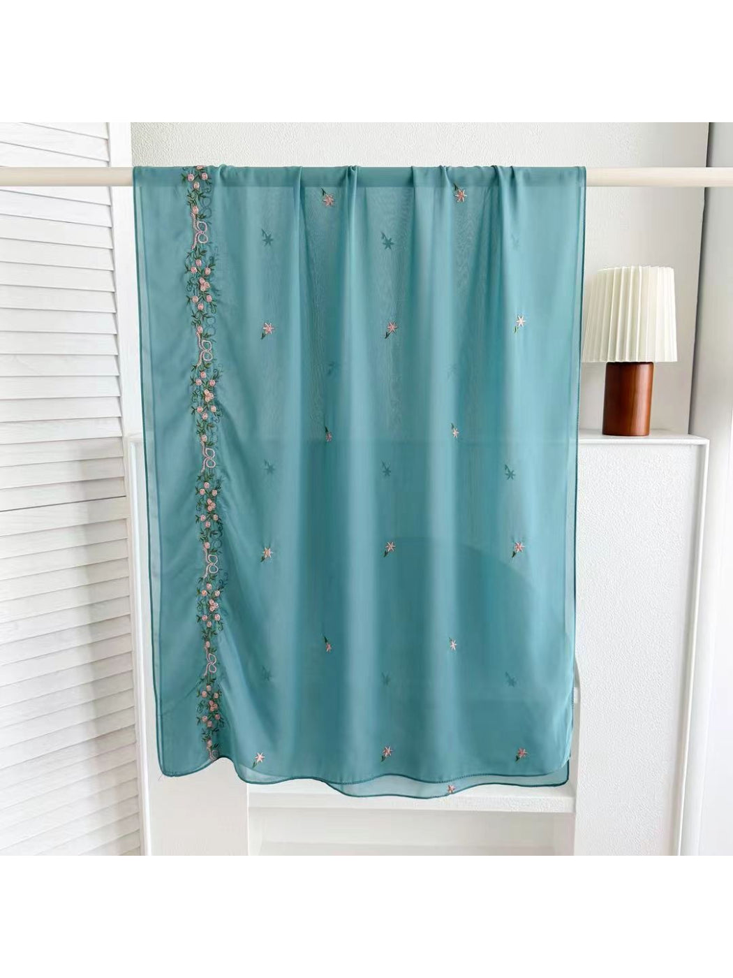 Soft scarf with botanical embroidery folded neatly on wooden surface