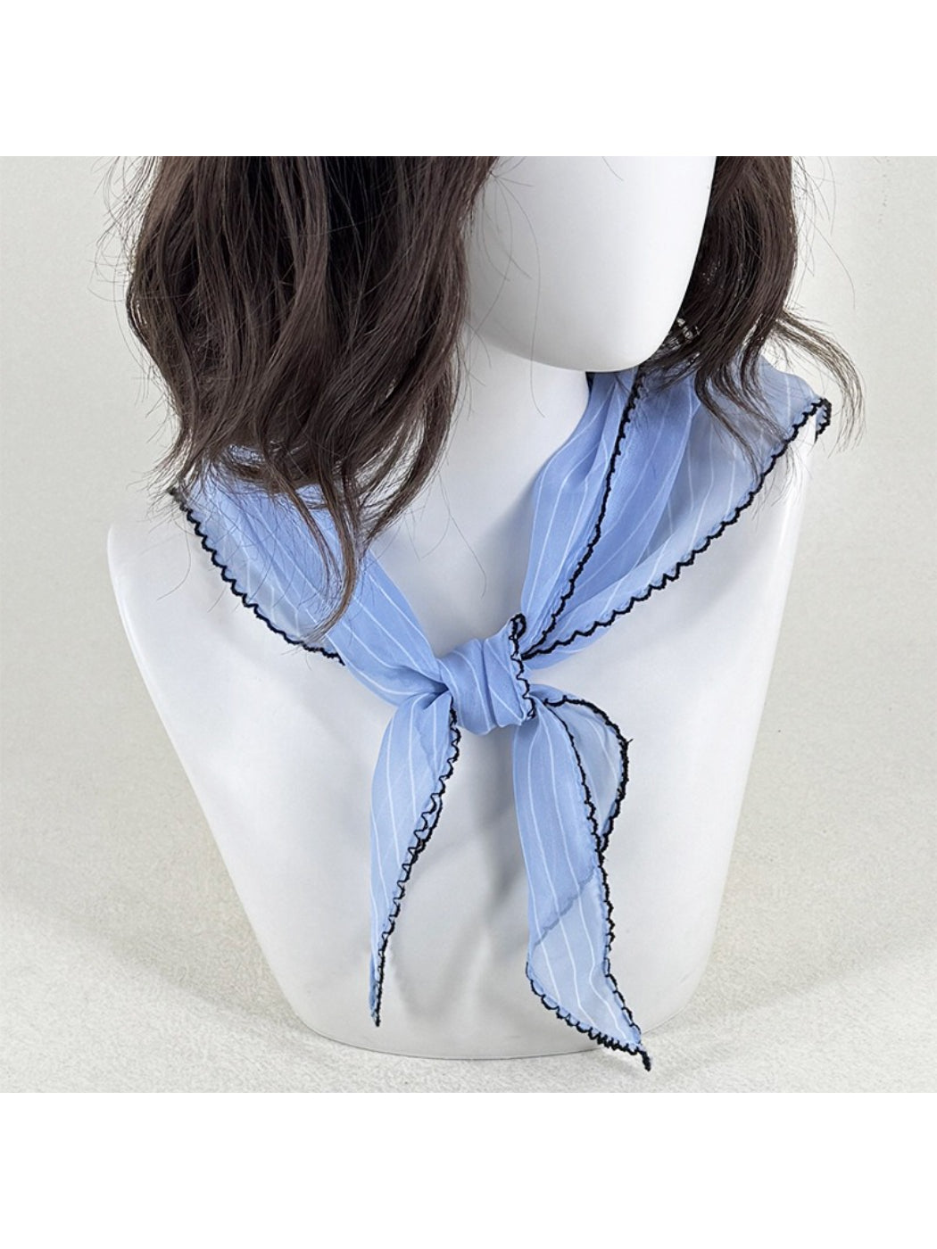 Close-up of pleated fabric and contrast trim detail on Scarvii triangle scarf