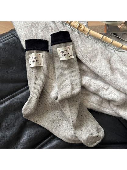 Rufia speckle knit crew socks folded neatly on wooden surface