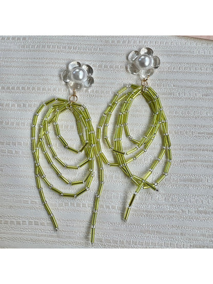 Earwish green bead dangle earrings hanging from a jewelry stand with soft lighting