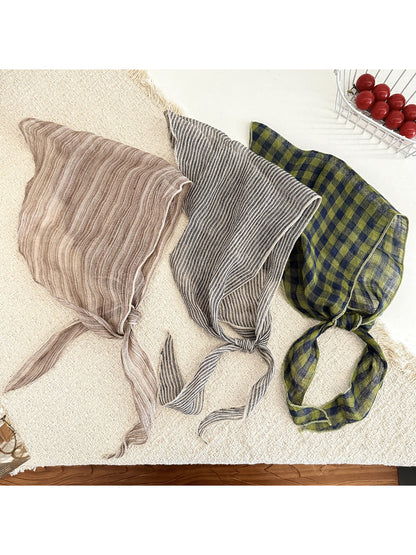 Close-up of Scarvii triangle scarf fabric showing beige and black plaid pattern with red accents