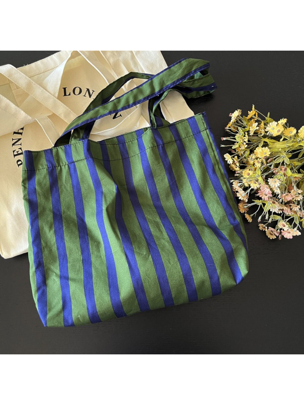 Cosbai green stripe shoulder tote bag hanging on a hook against white background
