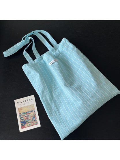 Cosbai sky blue tote bag held by hand showing size and portability