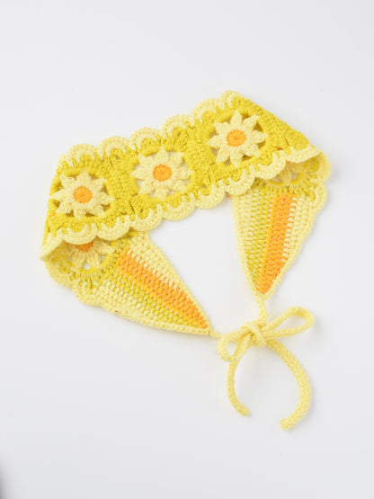 Crochet flower hairband laid flat on a wooden surface