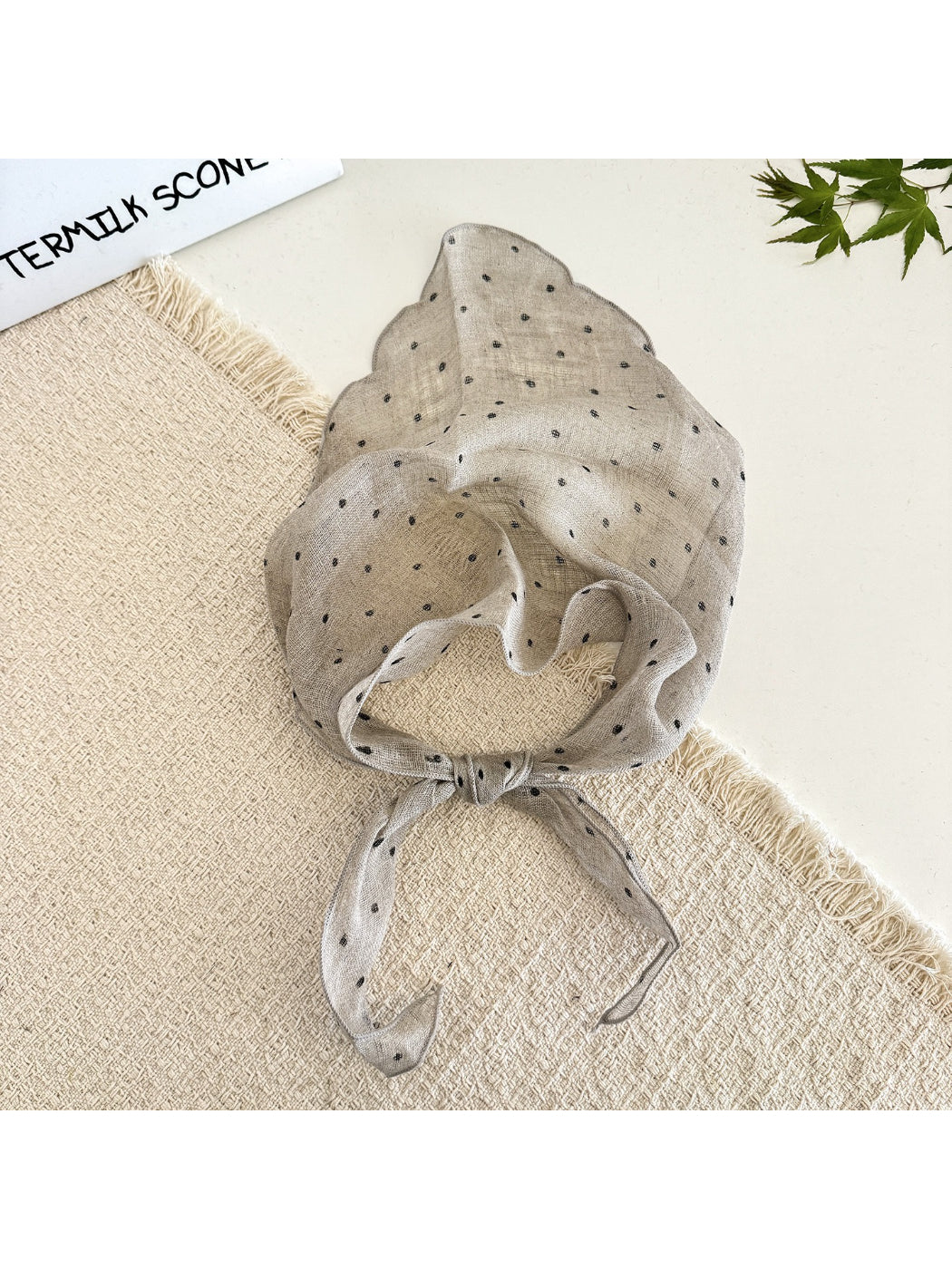 Model styling the polka dot head scarf as a neck accessory with casual outfit