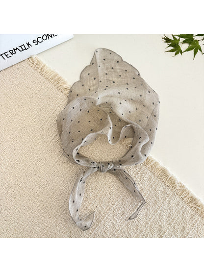 Model styling the polka dot head scarf as a neck accessory with casual outfit