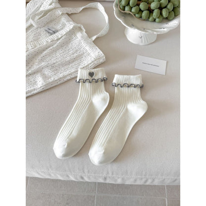 Pair of Rufia socks on wooden surface emphasizing cuff and heart details