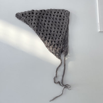 Beige crochet hollow-out hairband displayed flat on wooden surface