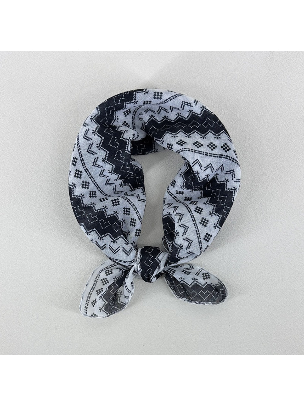 Close-up of Scarvii square scarf fabric with intricate geometric shapes in blue and beige