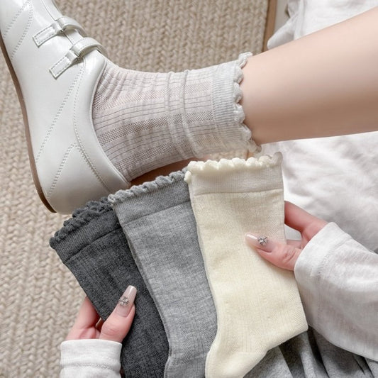 Pair of white crew socks with simple ruffle trim on a white background