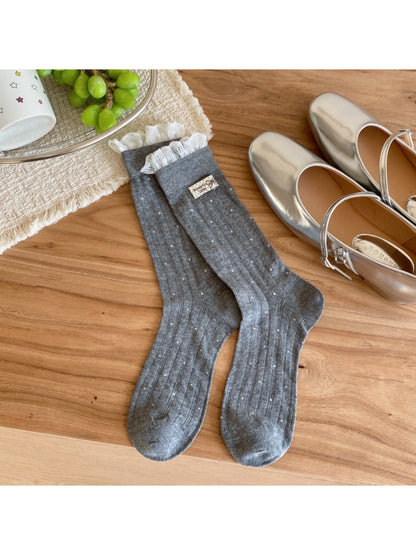 Flat lay of beige ribbed socks with evenly spaced black polka dots
