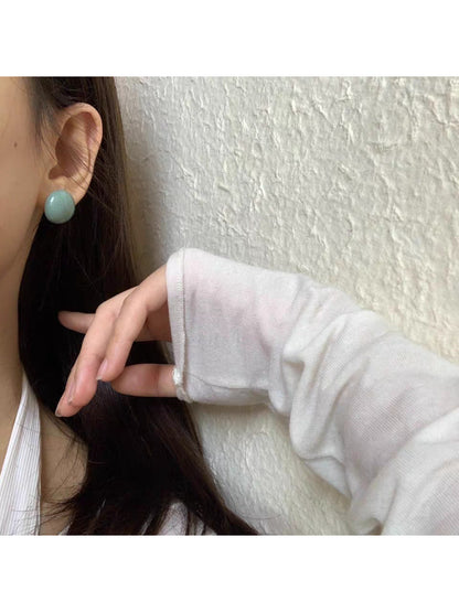 Close-up of glossy round stud earrings showing reflective surface and metal posts