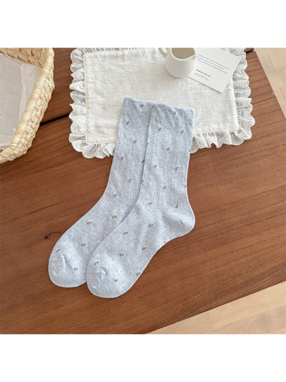 Rufia socks displayed with matching floral accessories on wooden surface