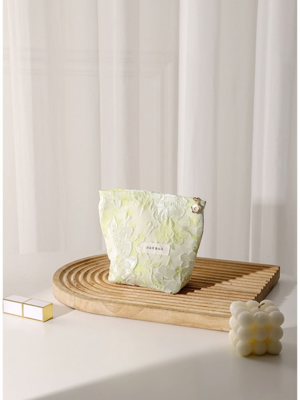 Cosbai floral cosmetic bag placed on a white surface with flowers in background