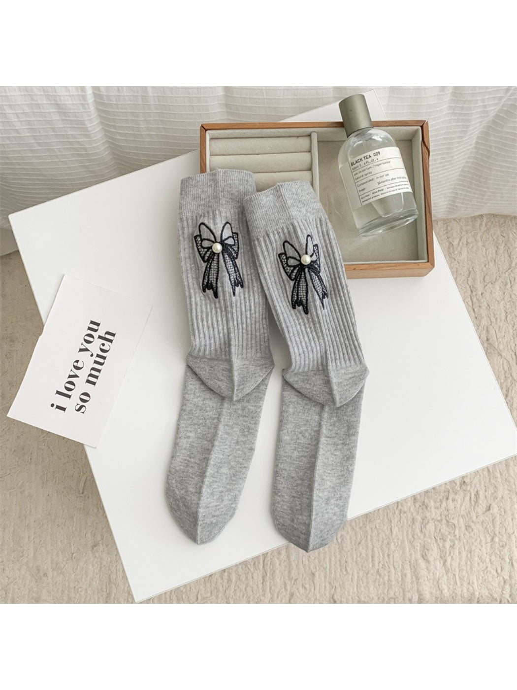 Stack of Rufia crew socks in beige with visible bow accents on each pair