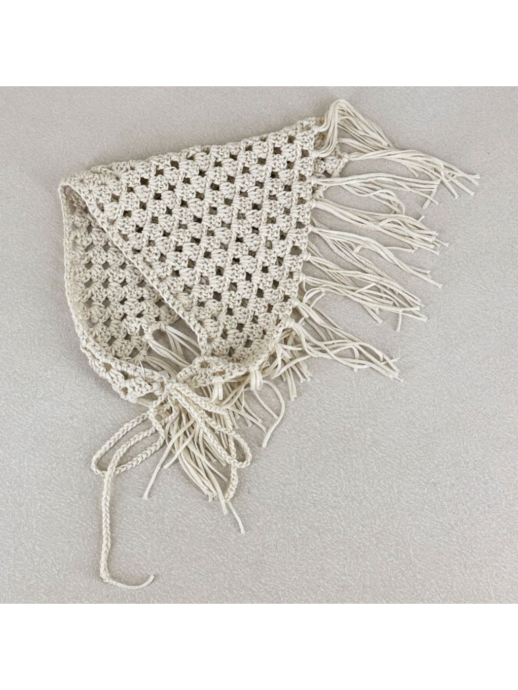 Model wearing the cream crochet bandana tied around the neck with tassels hanging