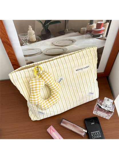 Plush charm attached to striped cosmetic bag zipper pull
