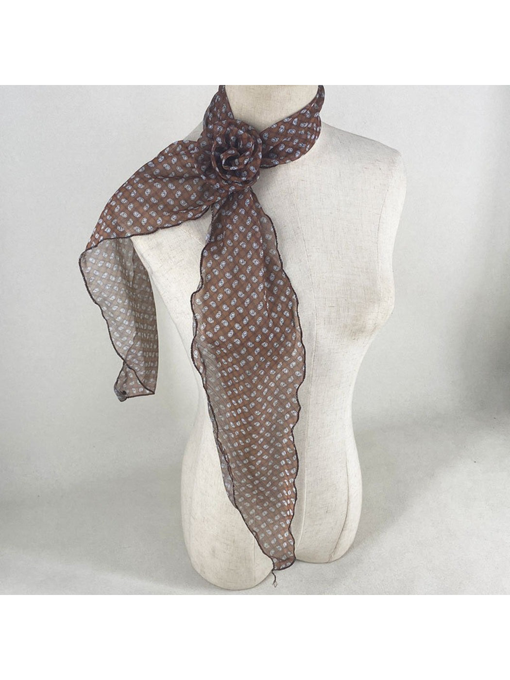 Scarf tied around neck showing detailed rose and polka dot design