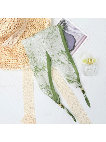 Detailed shot of the scarf's colorful print and delicate bead accents on sheer fabric