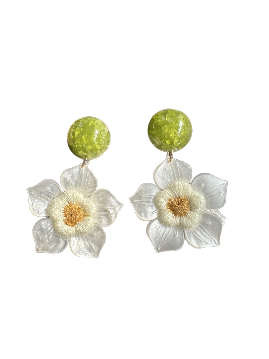 Earwish white flower drop earrings worn on a model's ear with a blurred background