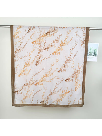 Scarvii wrap scarf draped over shoulders showcasing lightweight fabric and leaf pattern