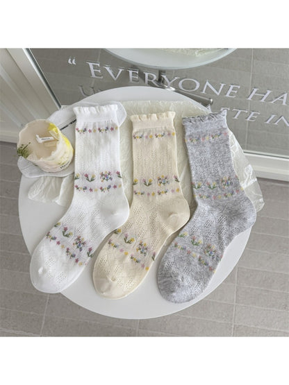 Rufia floral pointelle crew socks folded neatly on a wooden surface