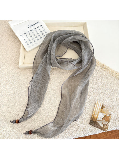 Close-up of pleated texture on a sheer skinny scarf in beige