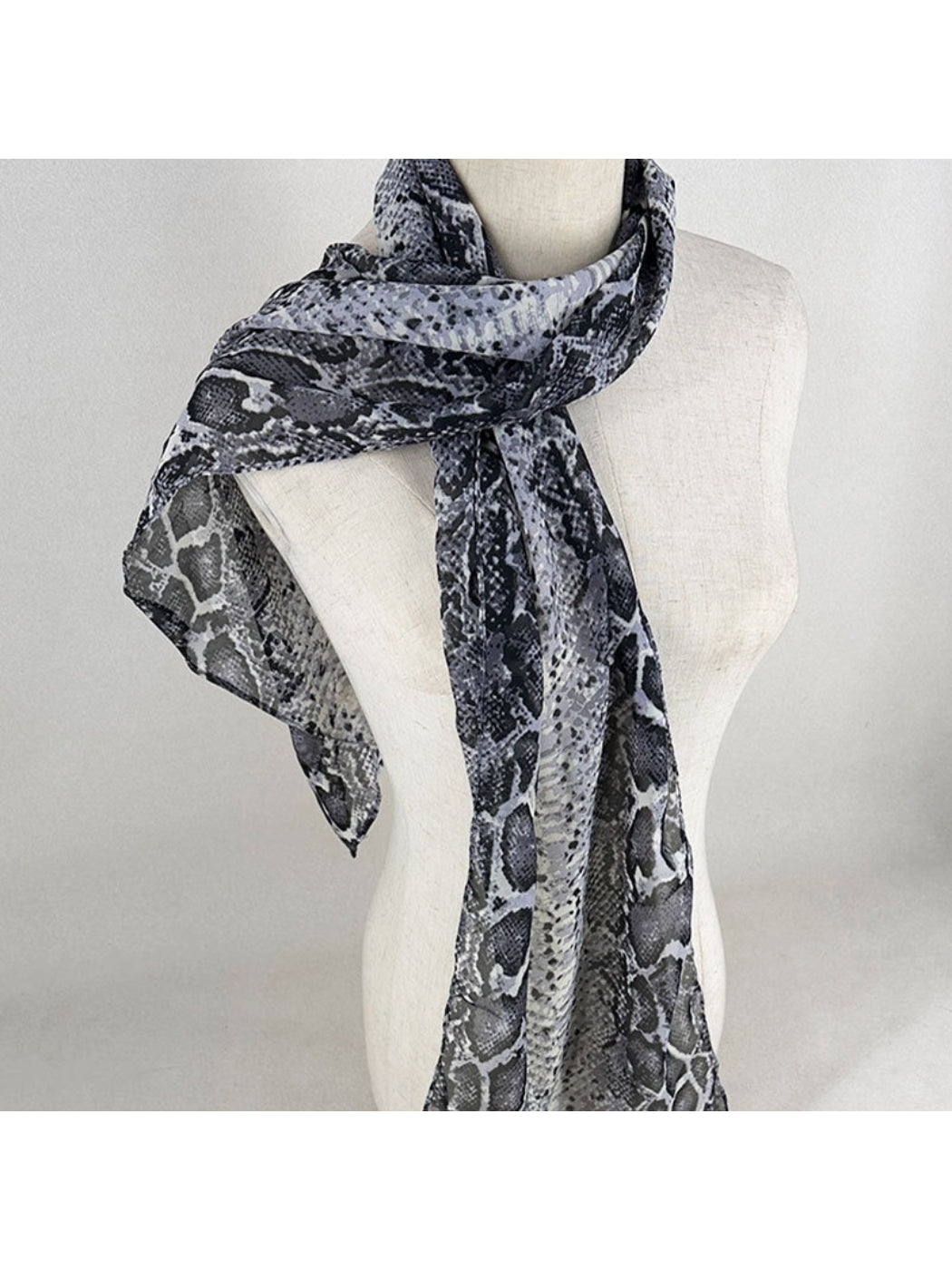 Model wearing monochrome snake print scarf styled around the neck