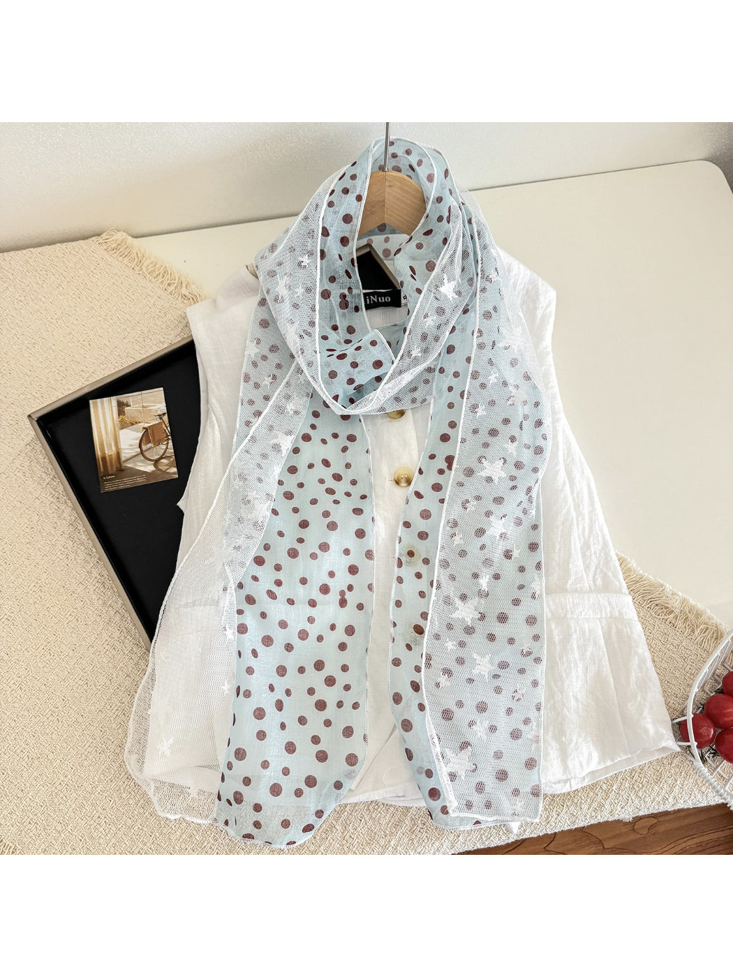 Folded Scarvii sheer scarf with white stars on black fabric on a wooden surface