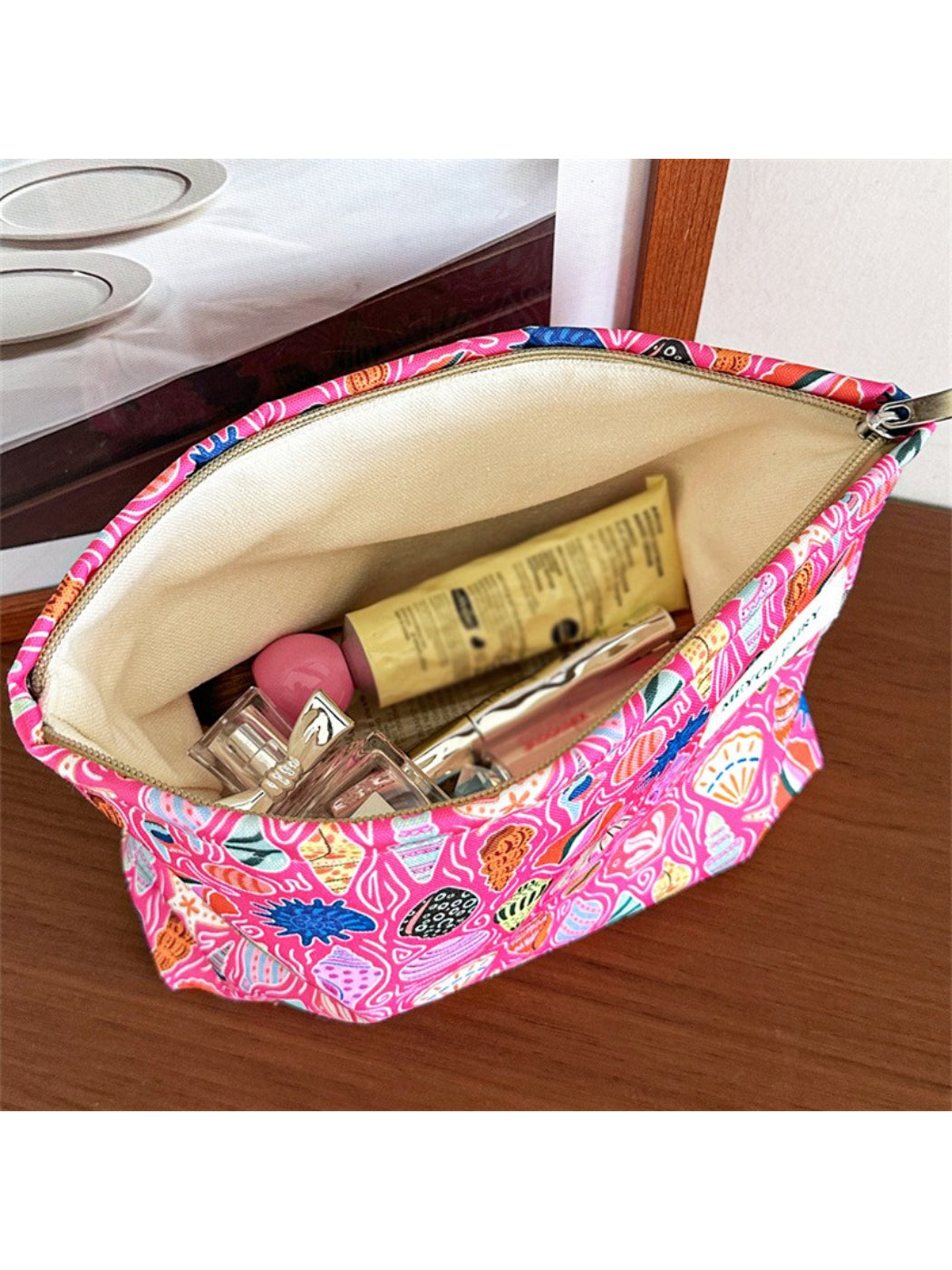 Cosbai pink shell makeup pouch displayed from a side angle emphasizing its compact size