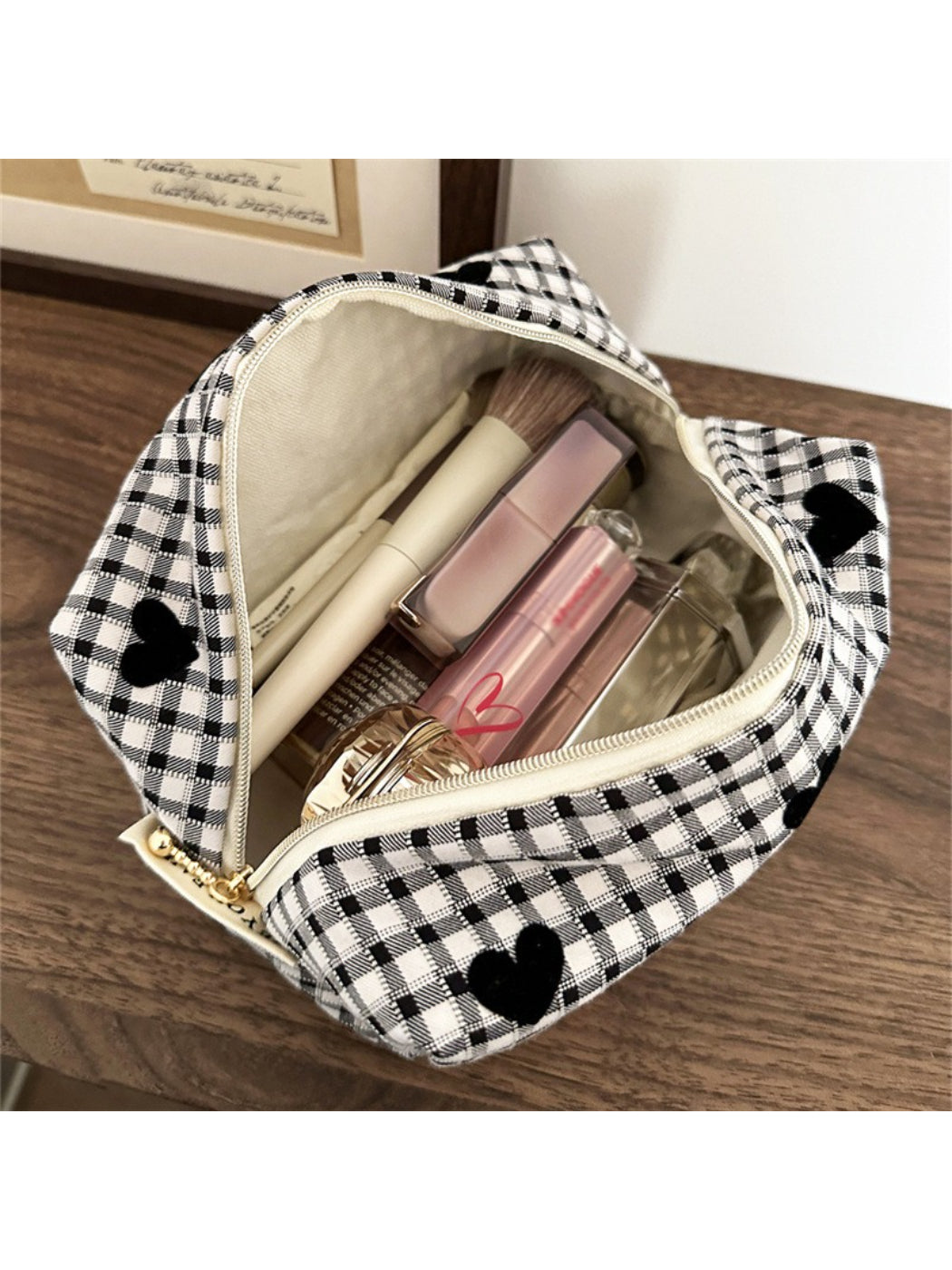 Black and white heart makeup bag placed next to cosmetics on a flat surface
