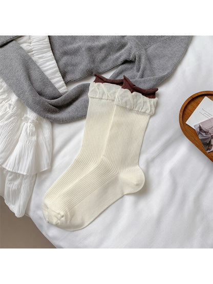 Rufia soft ribbed crew socks in beige paired with a cozy outfit on a wooden floor