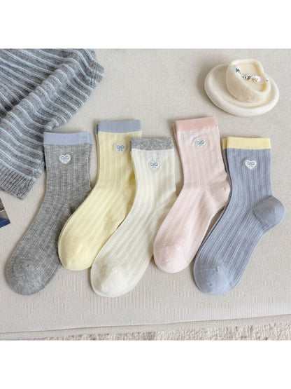 Pair of soft pastel socks with small heart details on a white background