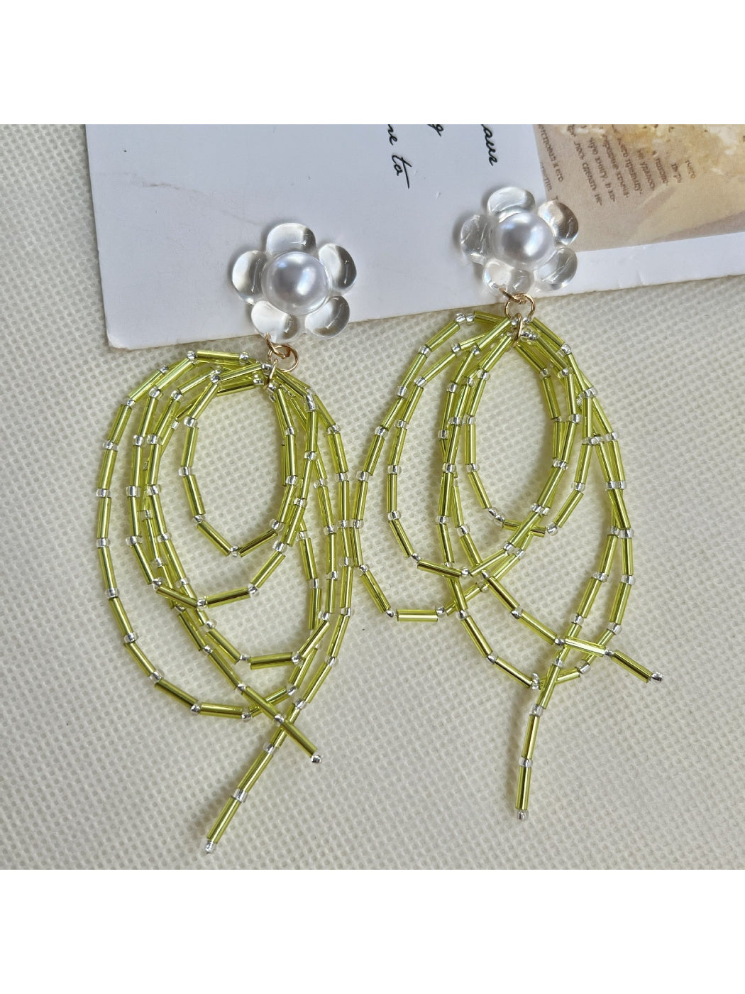 Pair of green bead dangle earrings displayed on a wooden surface