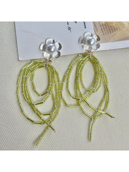 Pair of green bead dangle earrings displayed on a wooden surface