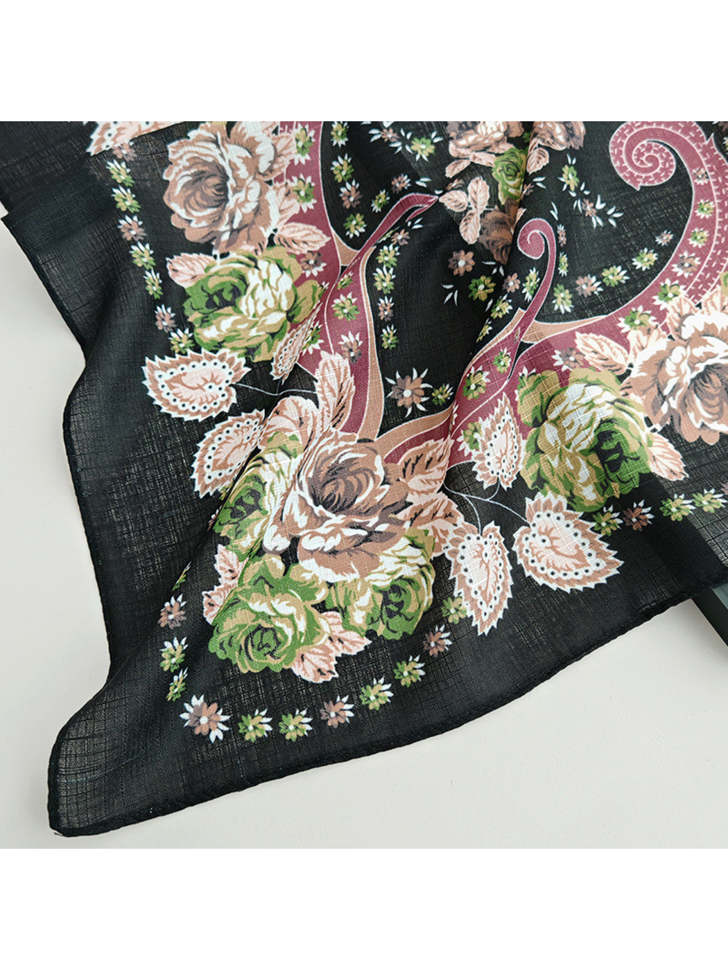 Close-up of a Black scarf corner showing rose motifs, paisley scrollwork and a narrow stitched edge
