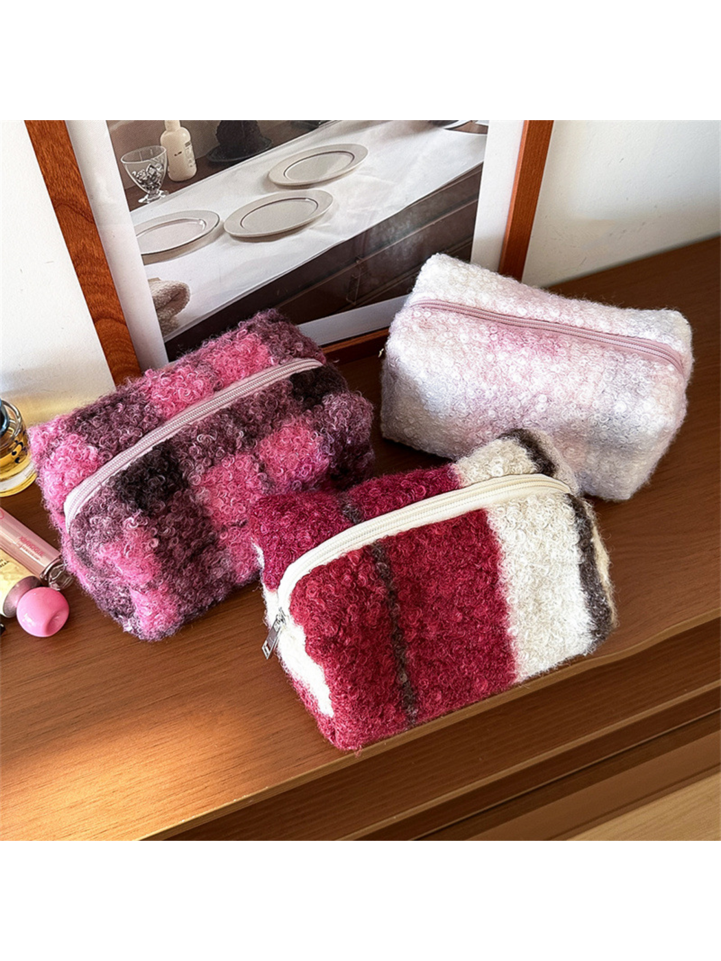 Red, Purple and Blush makeup bags viewed at an angle on a wooden tabletop