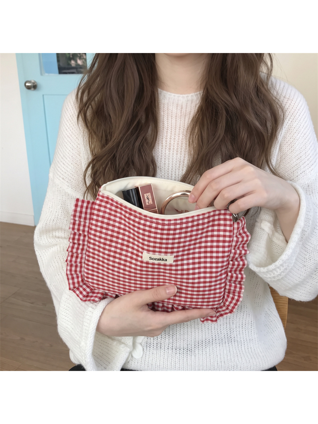 Red gingham makeup pouch held open, showing its cream-colored interior