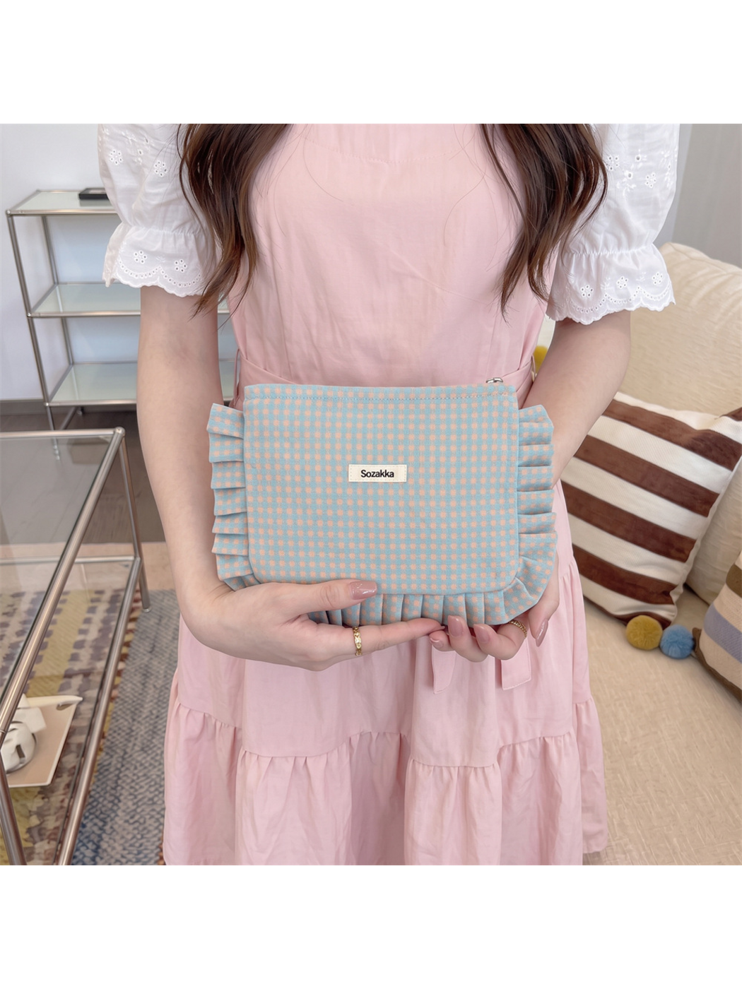 Orange makeup pouch with teal and peach checks held against a pink dress
