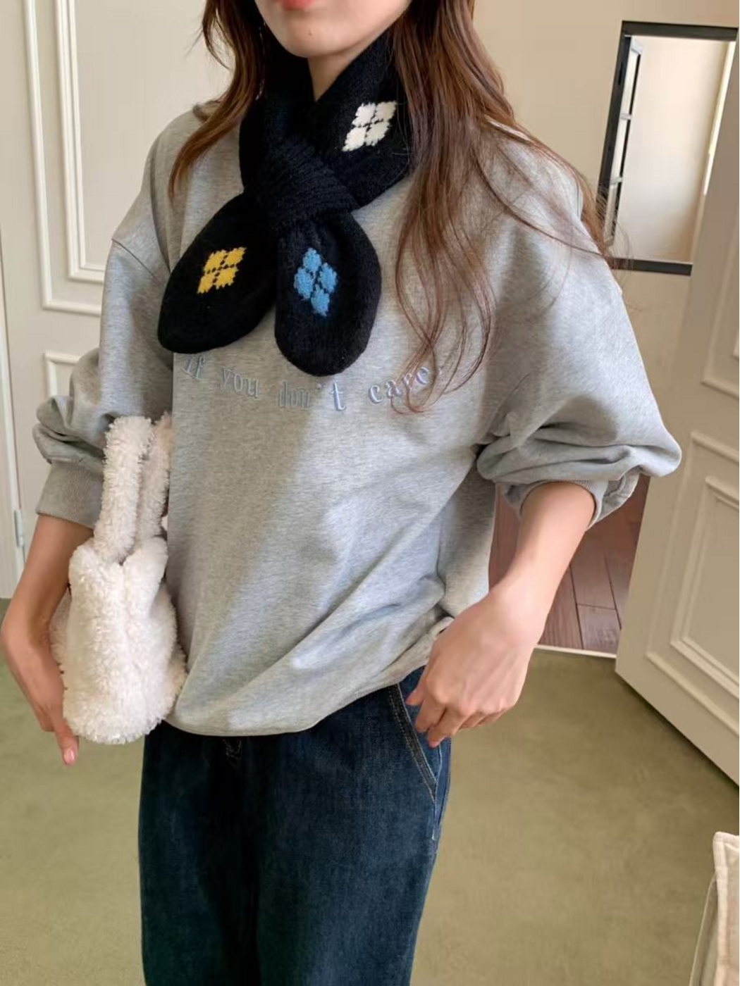 Black scarf worn over a gray sweatshirt, showing the crossover loop and yellow and blue end motifs