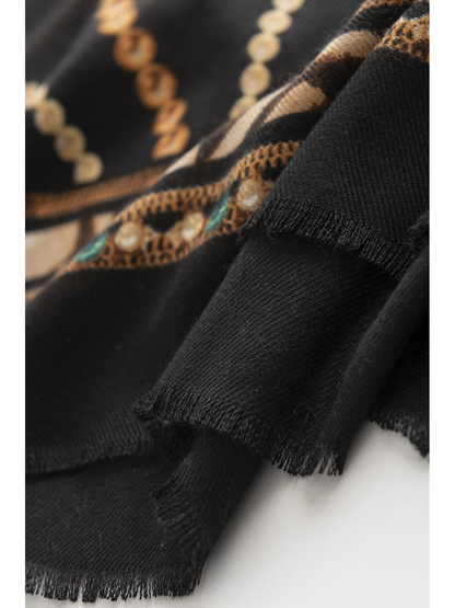 Close-up of Black scarf edges with short fringe, fine textile texture and a green-accented ornamental border