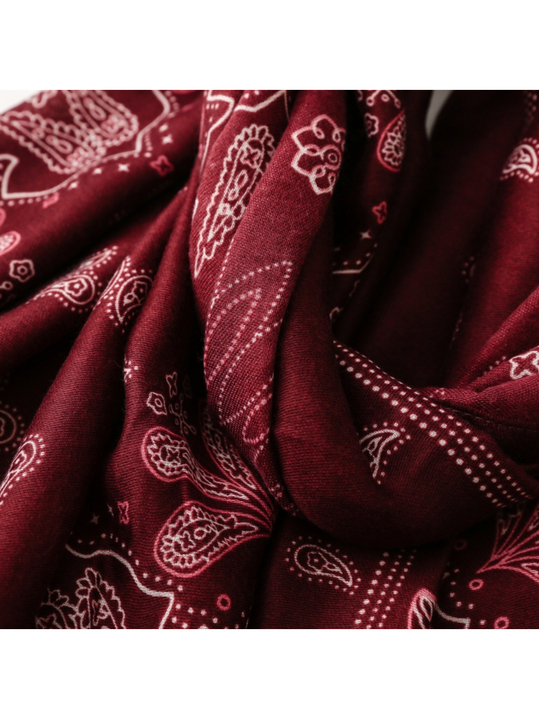 Close-up of pale paisley and floral motifs across dark red scarf folds
