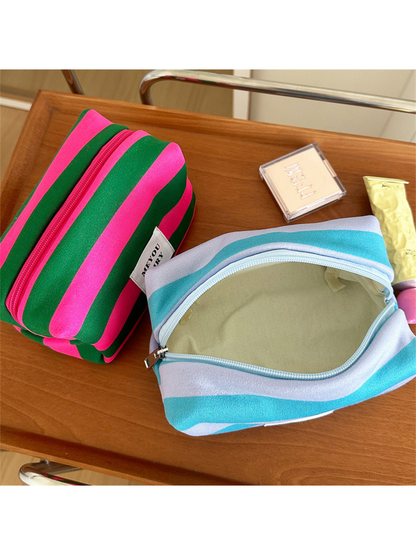 Open Turquoise striped makeup bag showing its pale lining beside a Green bag
