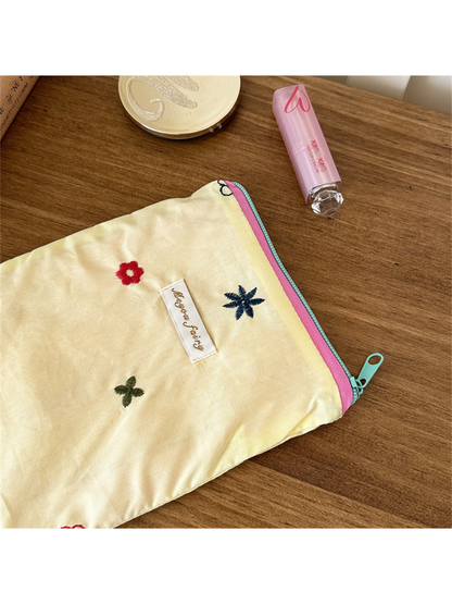 Close-up of Yellow pouch embroidery, script label and contrasting edge