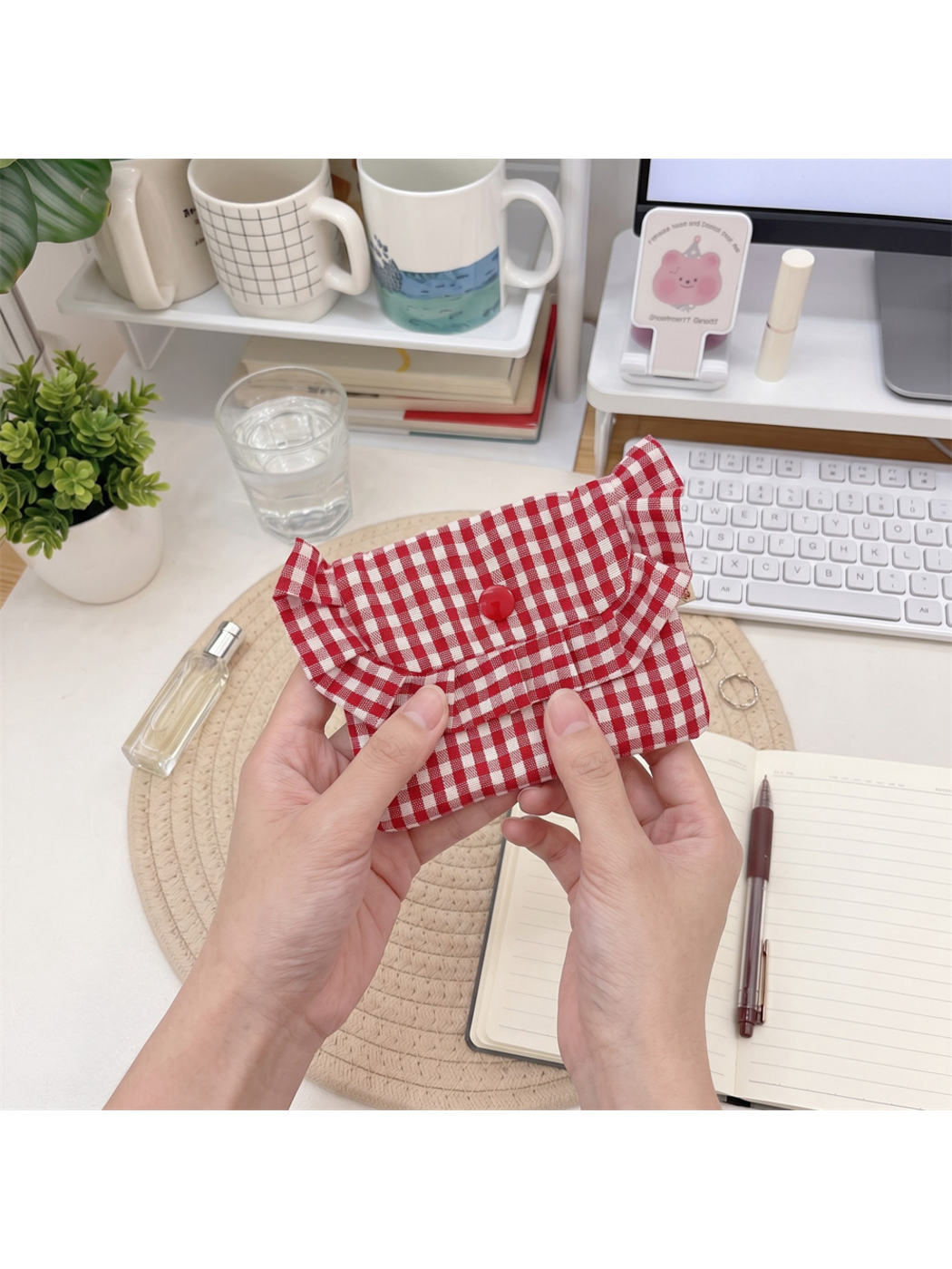 Red gingham coin purse held closed, with fingers lifting the ruffled flap edge