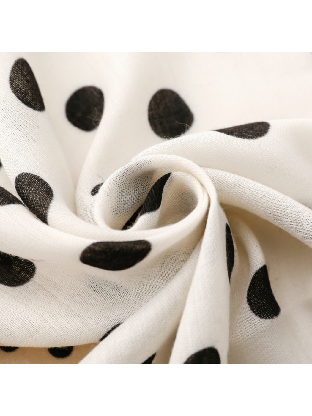 Close-up of black polka dots across softly curved scarf folds