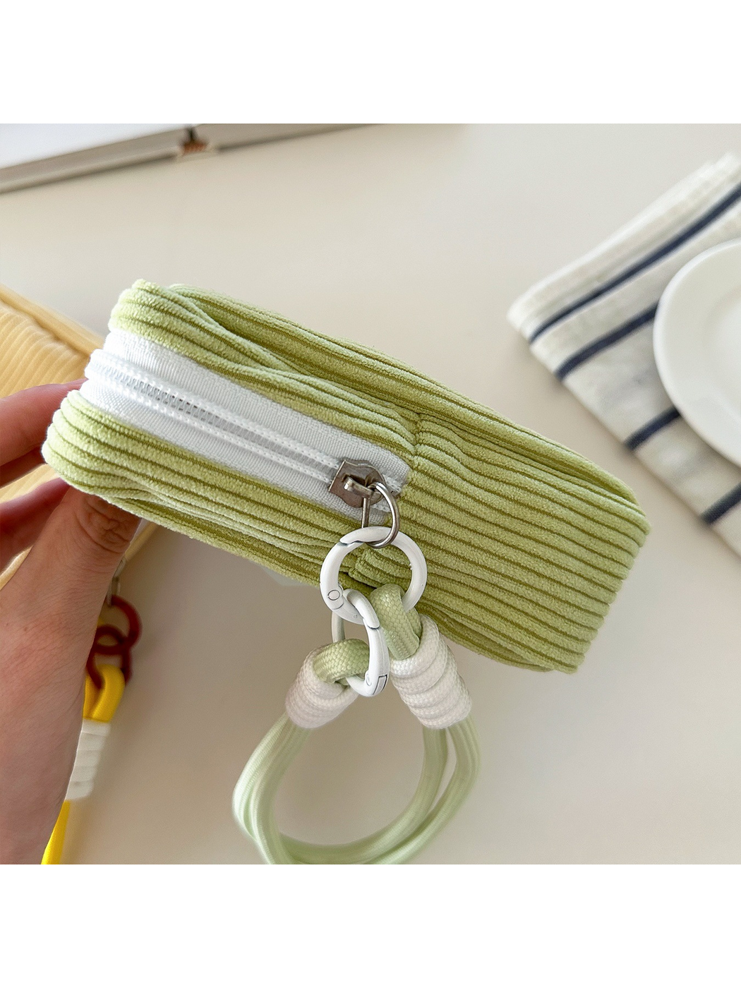 Close-up of Green makeup bag side ribs, white track and wrist-loop connecting rings