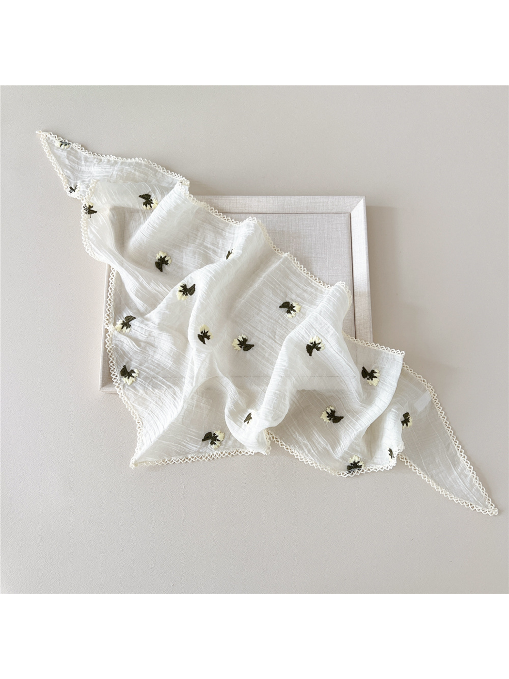 Cream triangle scarf draped open, showing floral embroidery and semi-sheer crinkled texture