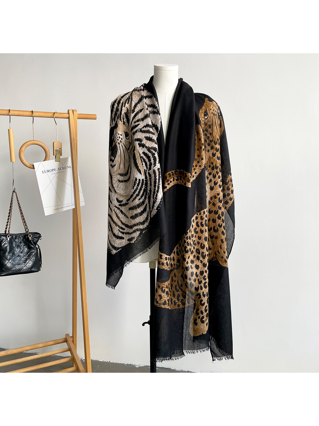 Black scarf hanging open on a mannequin with tiger and leopard motifs visible