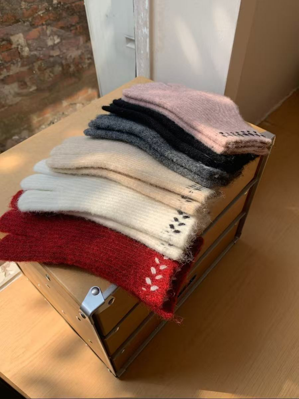 Gloves stacked in six colorways, showing cuff embroidery and fuzzy surfaces